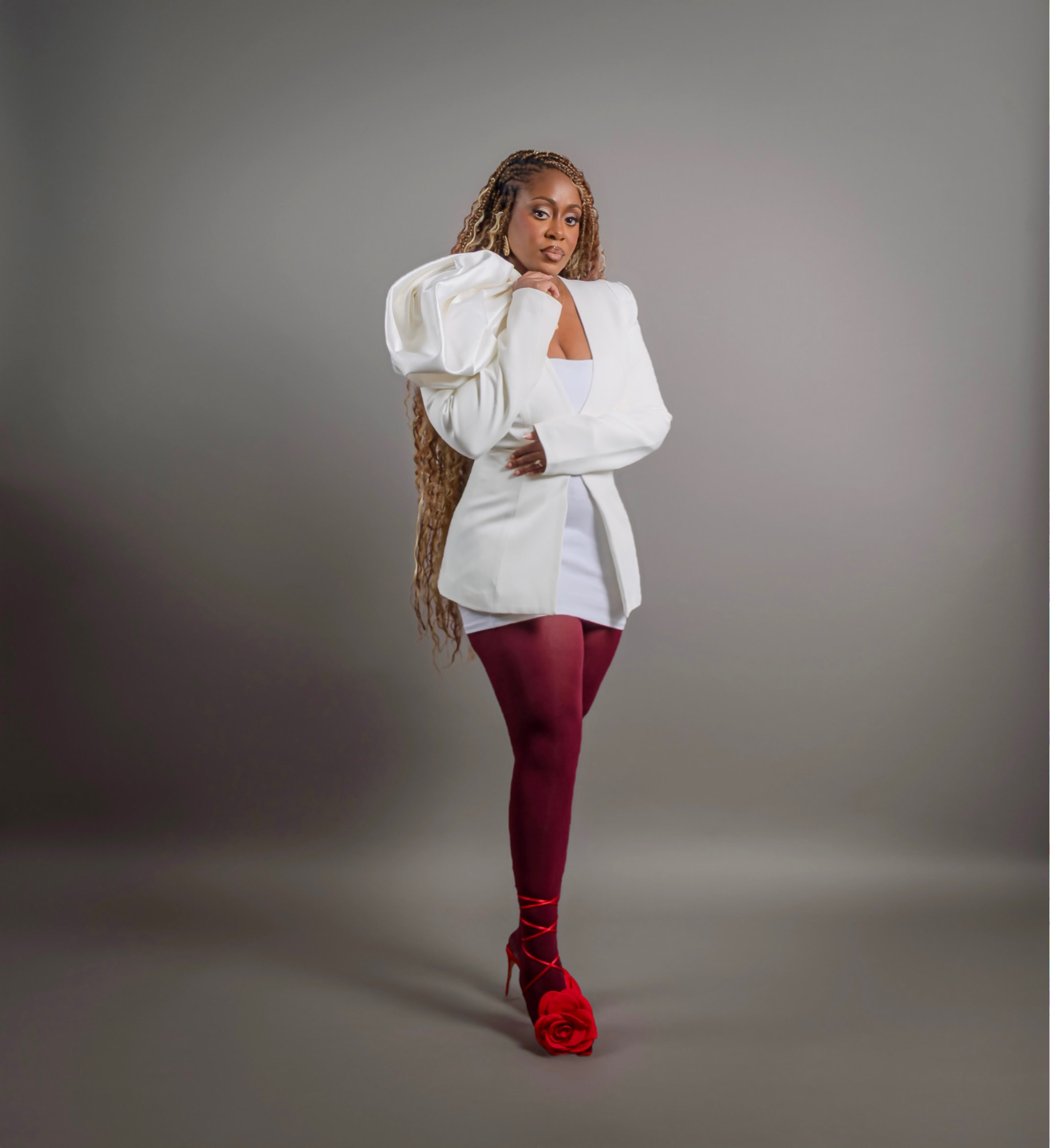 Hennrietta Dodoo full-length in a white sculptural blazer, oxblood tights and red rose heels